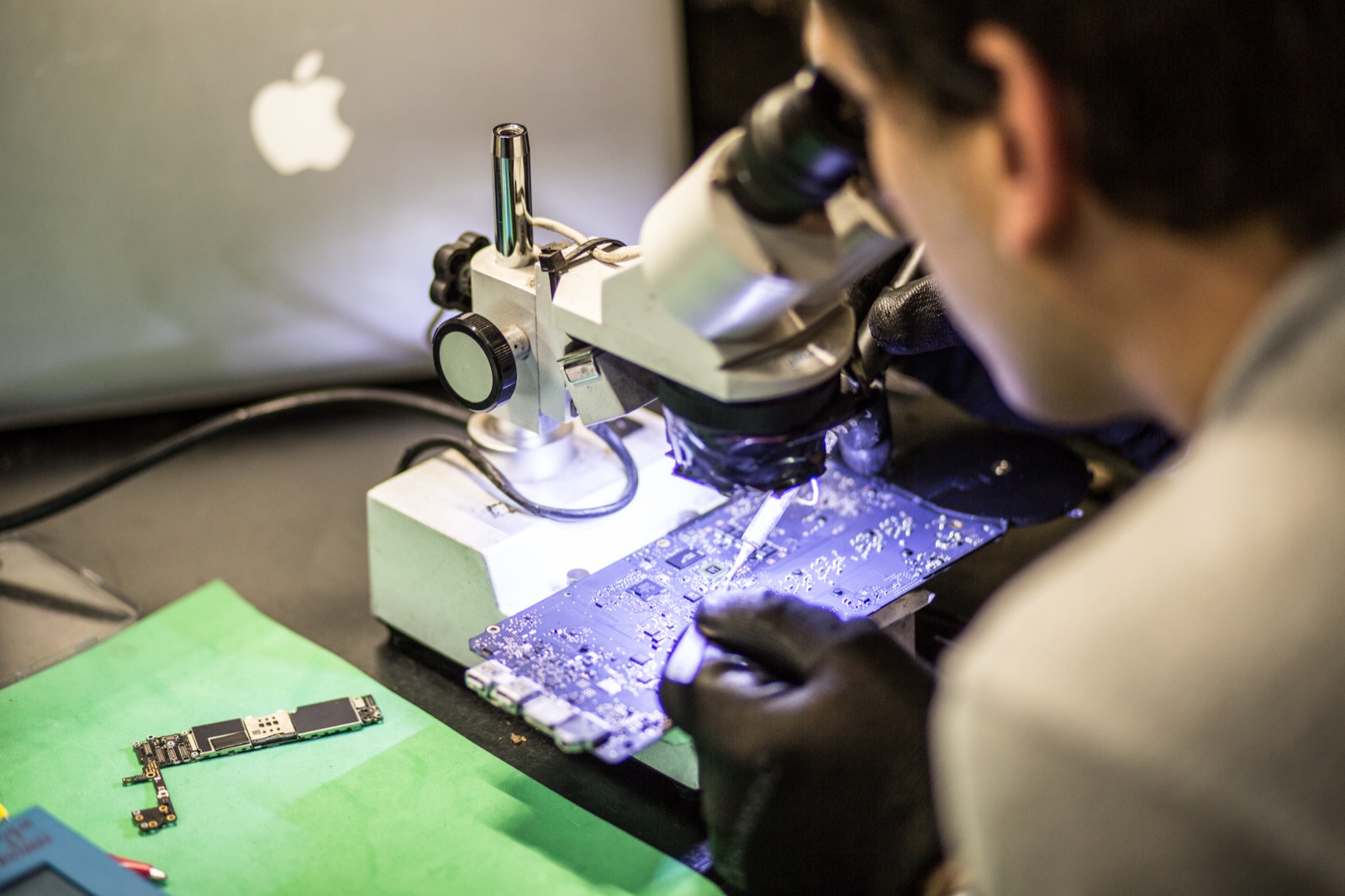 Técnico especializado Apple trabajando con microscopio en Teveotecno